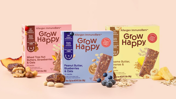 Three 'Grow Happy' snack bars with their packaging on a pink background